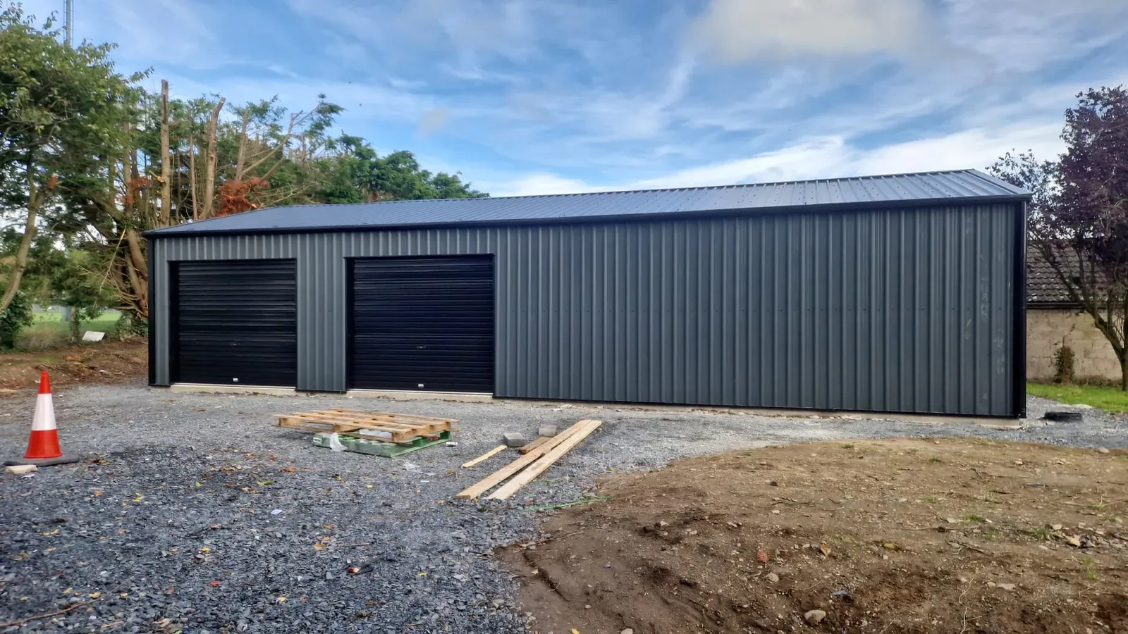 Grey steel double garage with two black roller doors